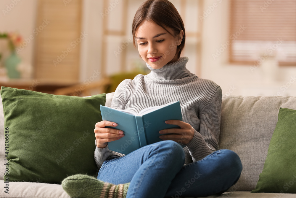 Beautiful young woman reading book on sofa at home Beautiful young woman reading book on sofa at home