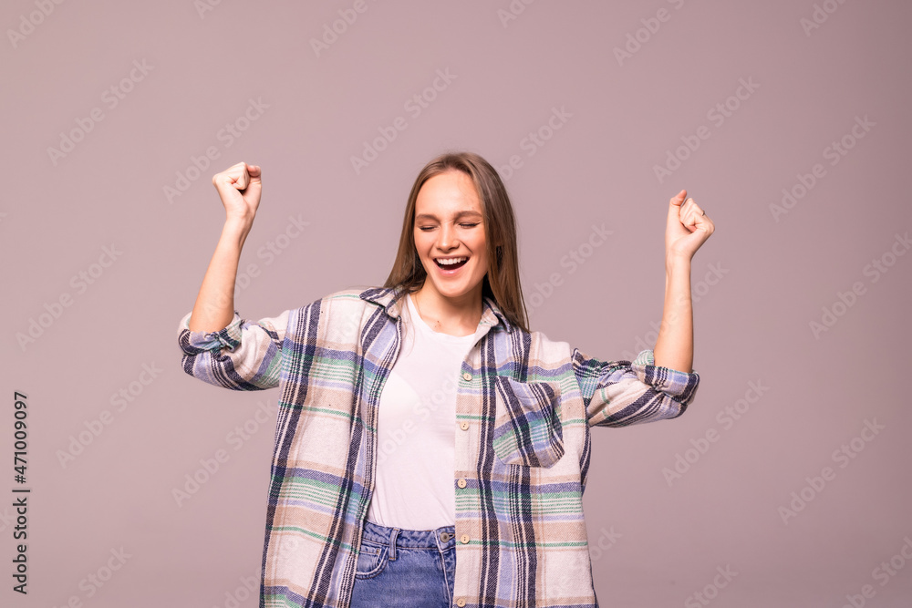 Young woman doing a winner gesture happy excited looking up with closed eyes isolated on white background Young woman doing a winner gesture happy excited looking up with closed eyes isolated on white background