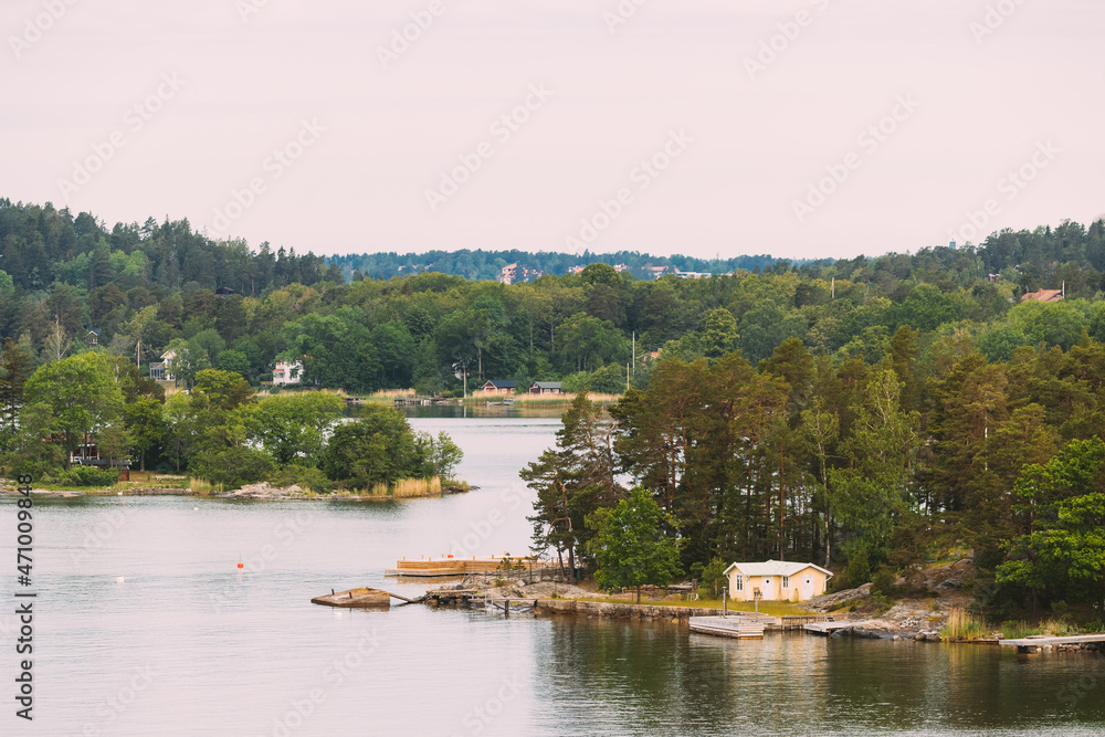 Sweden. Beautiful Swedish Wooden Log Cabins Houses On Rocky Island Coast In Summer Day. Lake Or River Landscape