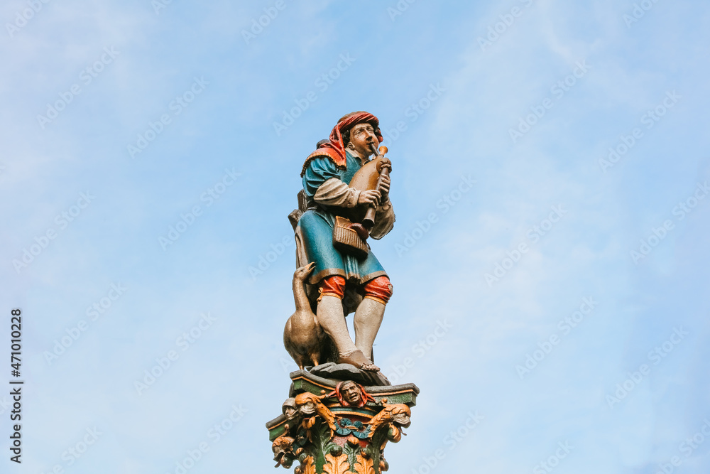 Pfeiferbrunnen, Bagpiper Fountain in Bern in Switzerland, The medieval statue, pillar, blue sky background Pfeiferbrunnen, Bagpiper Fountain in Bern in Switzerland, The medieval statue, pillar, blue sky background