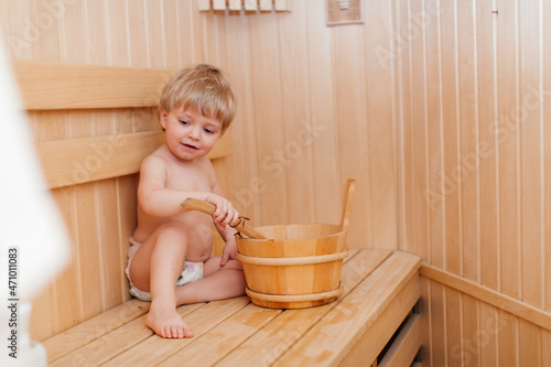 Beauty, healthcare. baby Boy relaxing in the sauna Toddler with broom and hat in russian sauna or bath