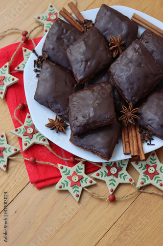 Italian traditional festive cookies called Mostaccioli or Mustaccioli on a plate on red napkin with festive decorations on wooden table. Christmas cookies made mith Pisto, a mix of various spices photo