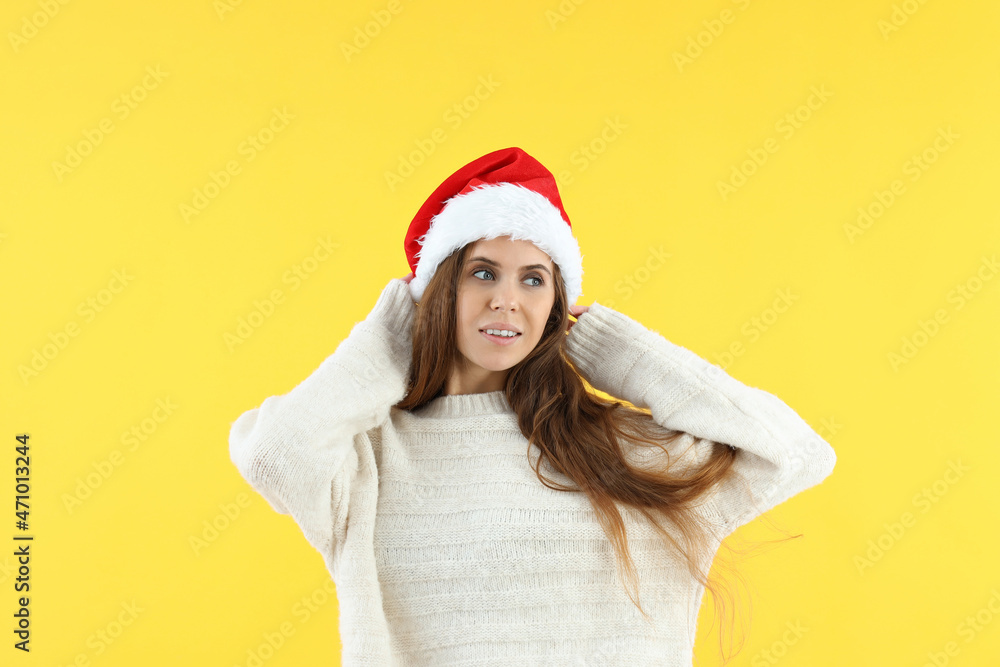 Attractive woman in Santa hat on yellow background Attractive woman in Santa hat on yellow background