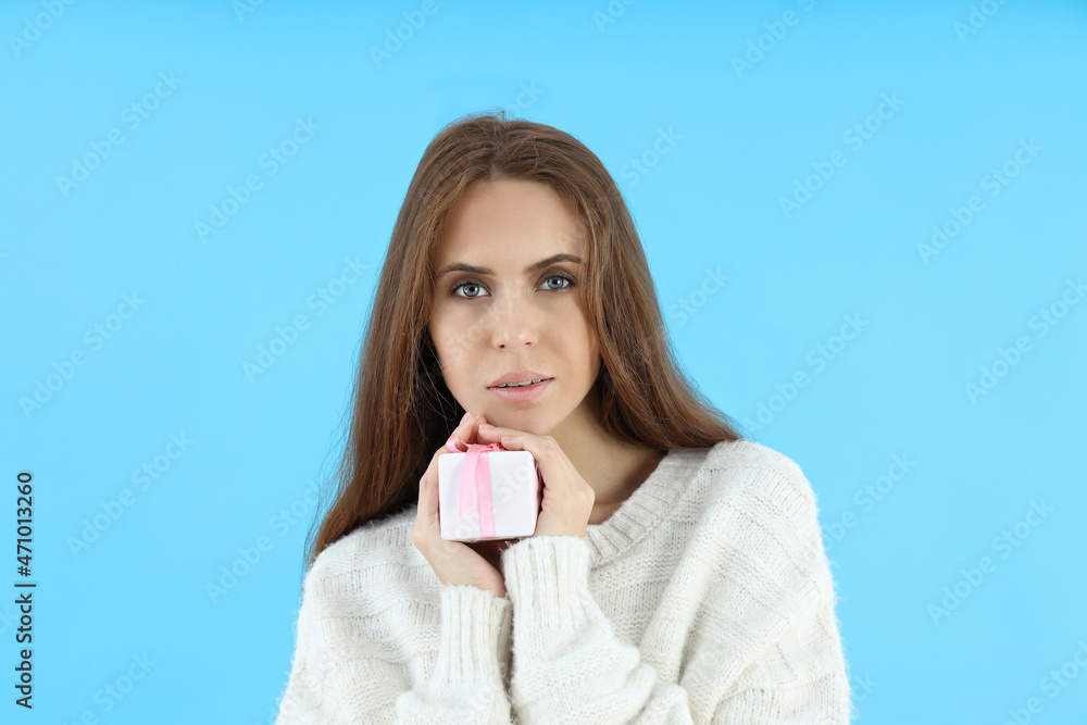 Attractive woman holds gift box on blue background Attractive woman holds gift box on blue background