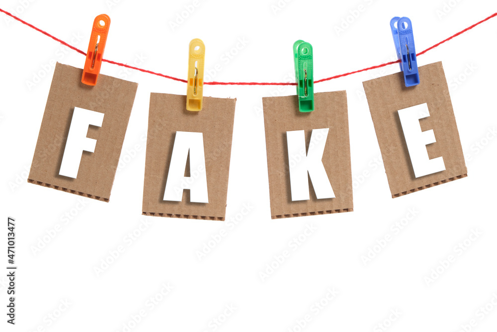 Inscription fake, white letters hung on clothespins, on white background. Inscription fake, white letters hung on clothespins, on white background.