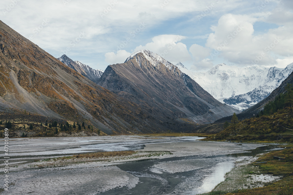 Scenic autumn landscape with many water streams in valley with view to big rock with snow on top and beautiful high snowy mountains in sunshine. Mountain creek and great snow-covered mountain wall. Scenic autumn landscape with many water streams in valley with view to big rock with snow on top and beautiful high snowy mountains in sunshine. Mountain creek and great snow-covered mountain wall.