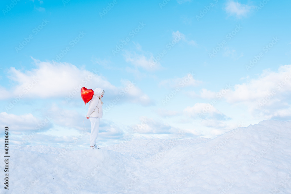 Fototapeta premium Woman in white clothes walk along shore of frozen sea or ocean with red heart-shaped balloon. Valentine, Arctic, Travel. Copy space