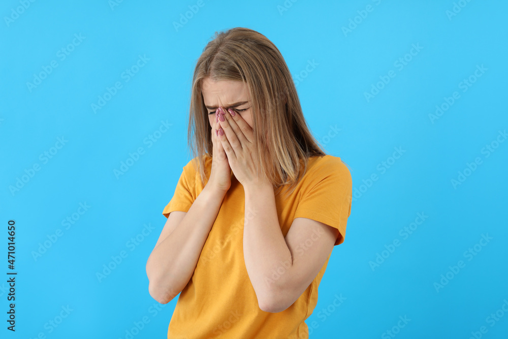 Crying girl in t-shirt on blue background Crying girl in t-shirt on blue background