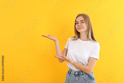 Young attractive girl in jeans on yellow background