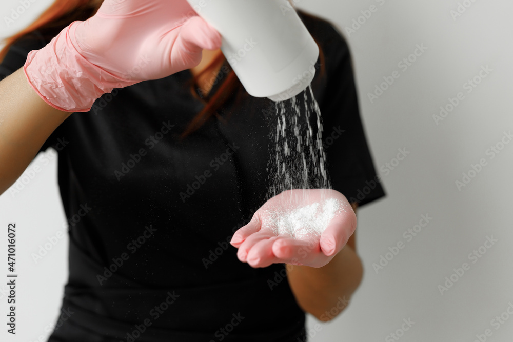 Redhead sugaring master in black robe and black gloves putting some powder in her hand Redhead sugaring master in black robe and black gloves putting some powder in her hand