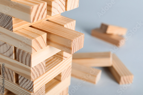 Jenga tower made of wooden blocks on grey background  closeup. Space for text