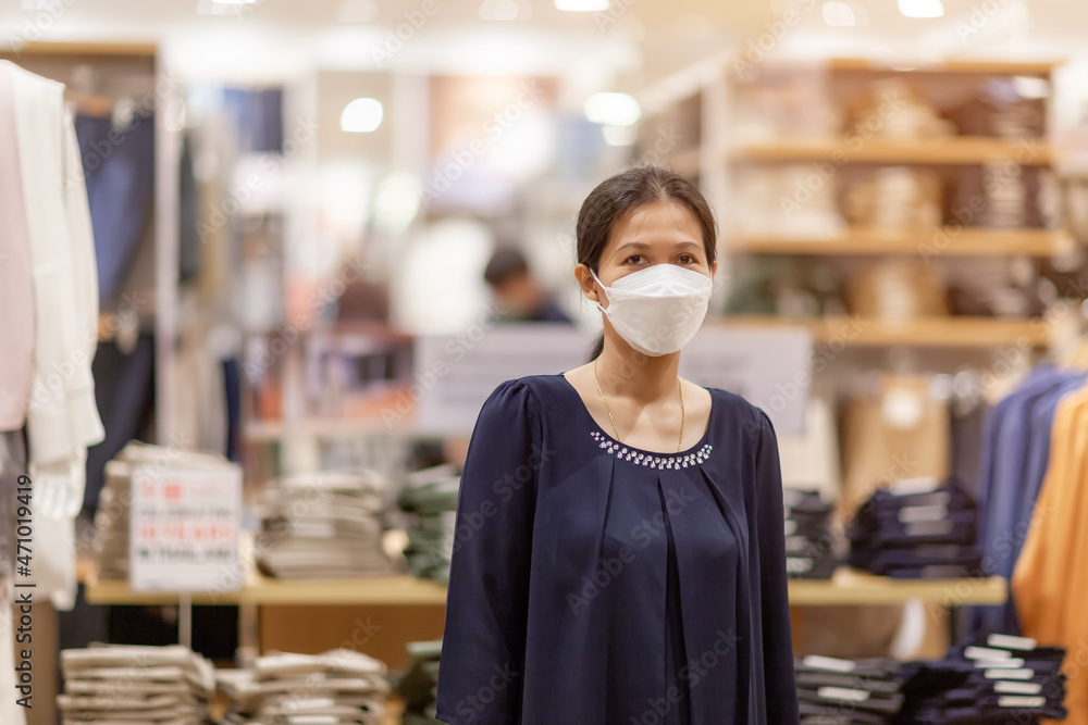 Adult woman in medical mask in a store. Buying clothing at the supermarket. Visiting public places during the coronavirus pandemic Adult woman in medical mask in a store. Buying clothing at the supermarket. Visiting public places during the coronavirus pandemic