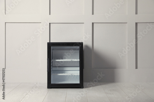 Empty mini bar with glass door near beige wall indoors. Space for text