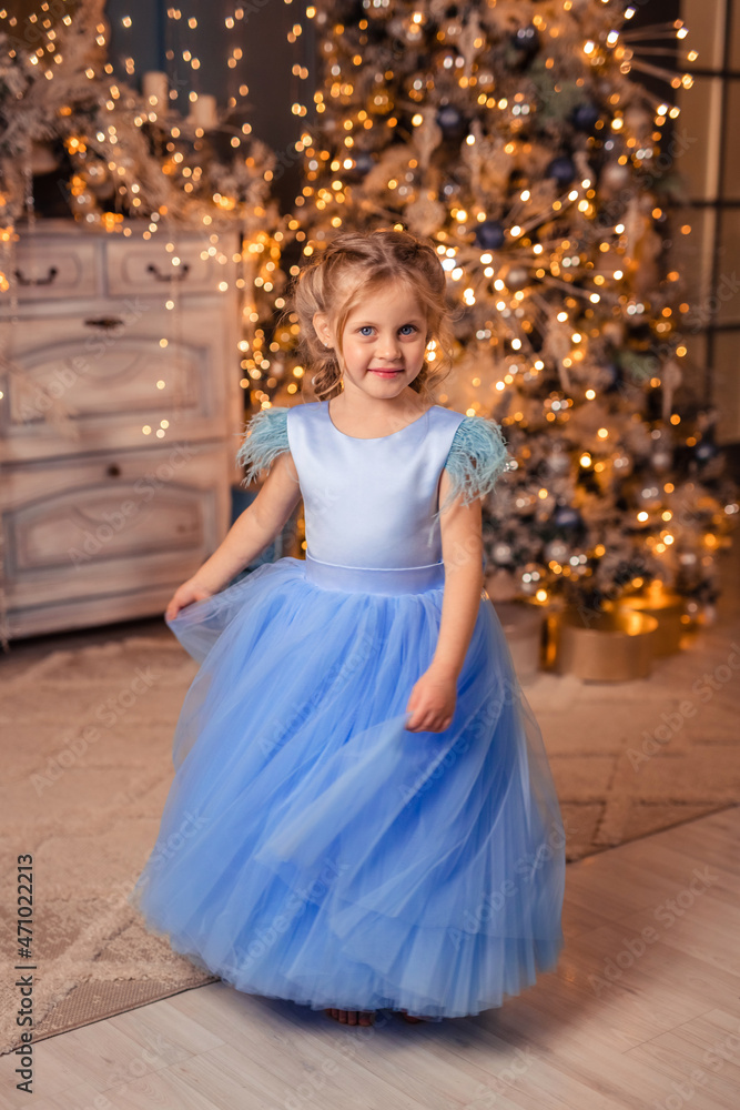 beautiful girl in an elegant dress against the background of Christmas lights and a Christmas tree in a beautiful interior