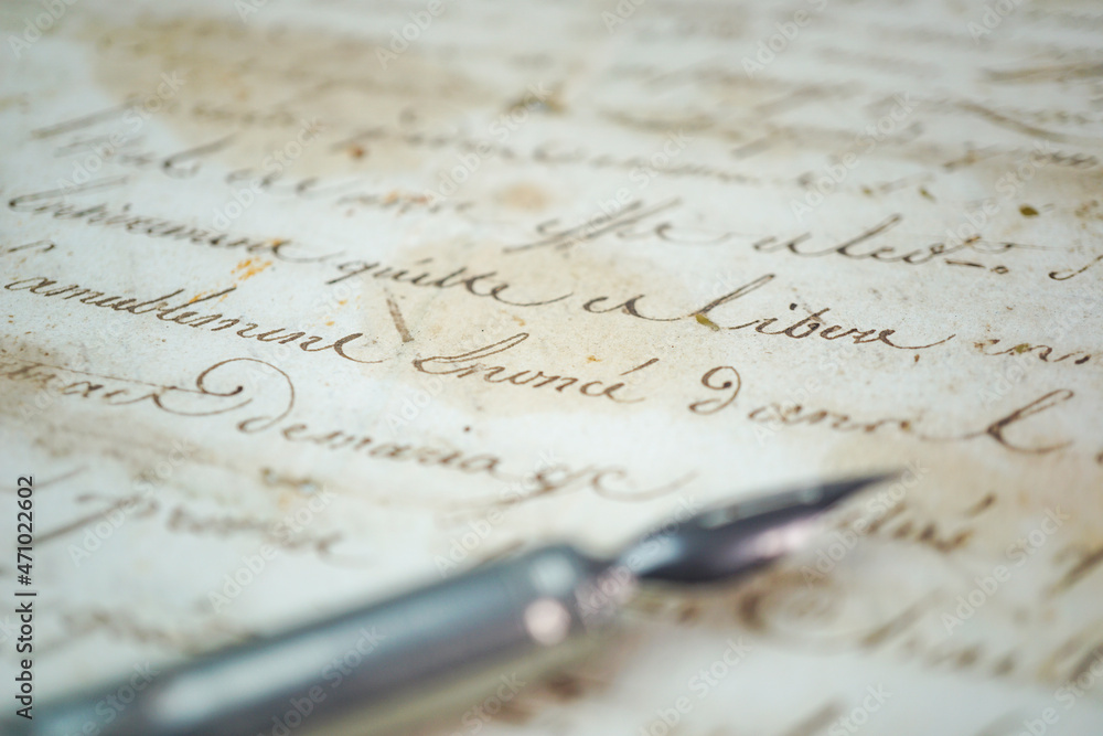 Foreground steel penholder and nib over an old manuscript Foreground steel penholder and nib over an old manuscript