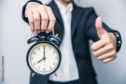 Fotografie Business people thumbs up with alarm clock for punctual good time or best timing