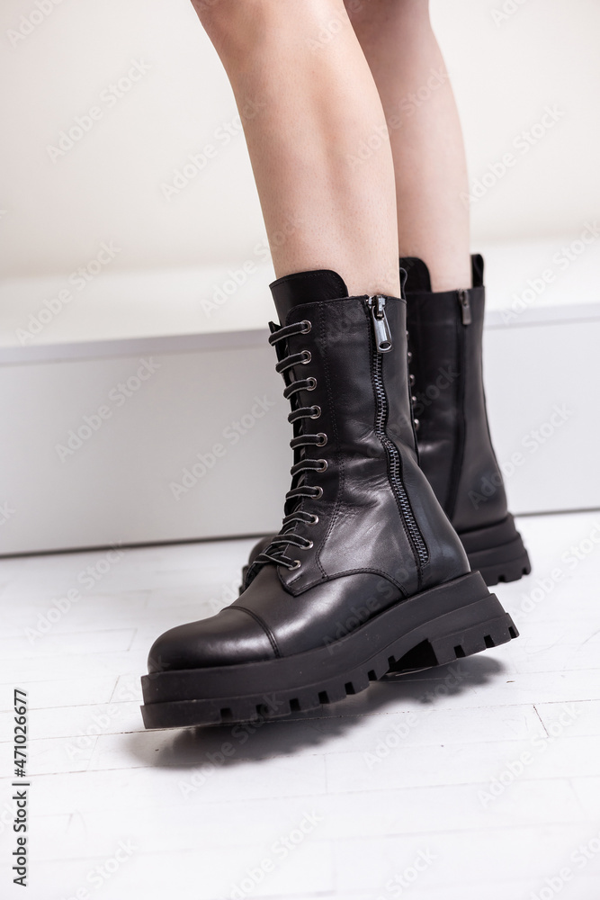 Beautiful female legs with fashionable black boots on the background in the studio. Women's stylish leather boots. Beautiful female legs with fashionable black boots on the background in the studio. Women's stylish leather boots.