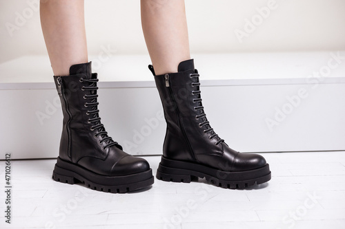 Beautiful female legs with fashionable black boots on the background in the studio. Women's stylish leather boots.