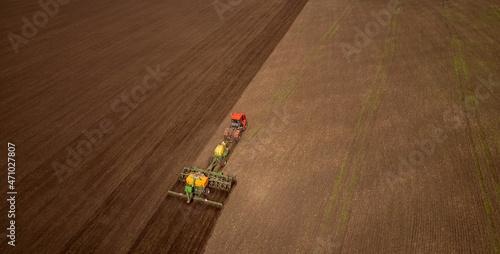 Farmer on tractor cultivates and plows plough land of field for planting cereals . Aerial top view Agriculture concept