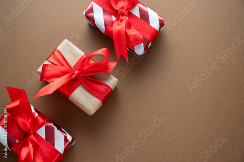 Christmas gift boxes with red bows on brown background, top view. Copy space.