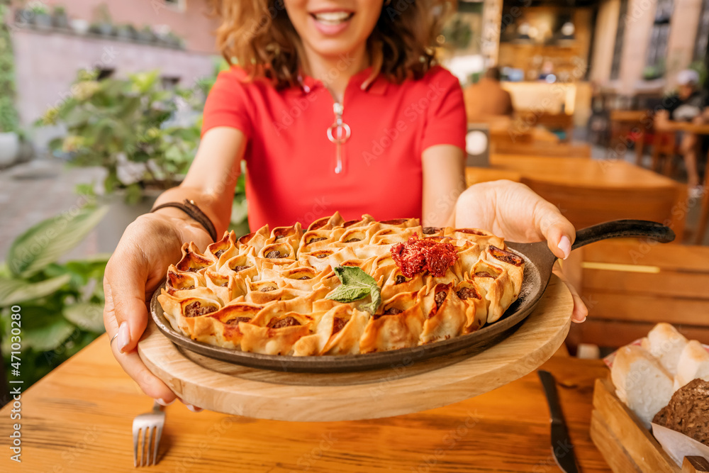 Woman eating opened manti or dumplings on a frying pan in restaurant. Traditional cuisine of Oriental and Turkic people Woman eating opened manti or dumplings on a frying pan in restaurant. Traditional cuisine of Oriental and Turkic people