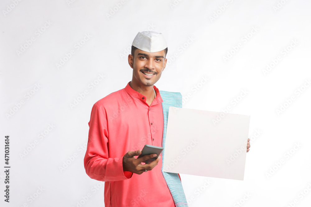 Young indian farmer holding white card board and using smartphone on white background. Young indian farmer holding white card board and using smartphone on white background.