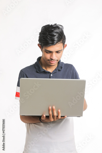 Young indian man using laptop over white background.