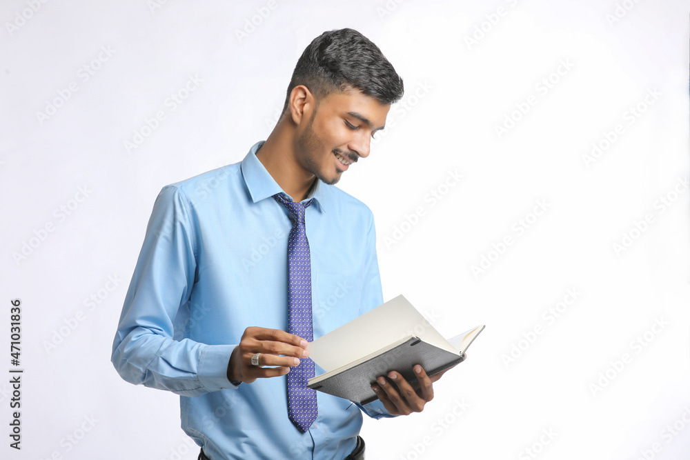 Young indian businessman cheaking or reading dairy on white background. Young indian businessman cheaking or reading dairy on white background.