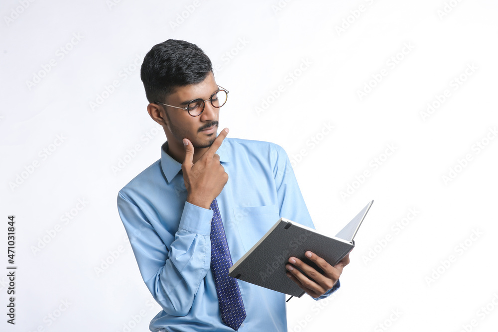 Young indian man holding diary in hand and thinking some idea Young indian man holding diary in hand and thinking some idea