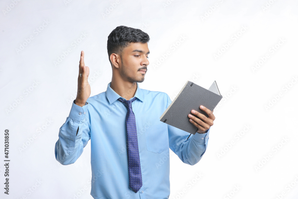 Young indian man holding diary in hand and thinking some idea Young indian man holding diary in hand and thinking some idea