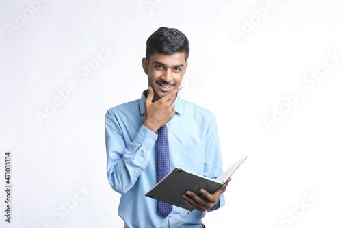 Young indian businessman cheaking or reading dairy on white background.