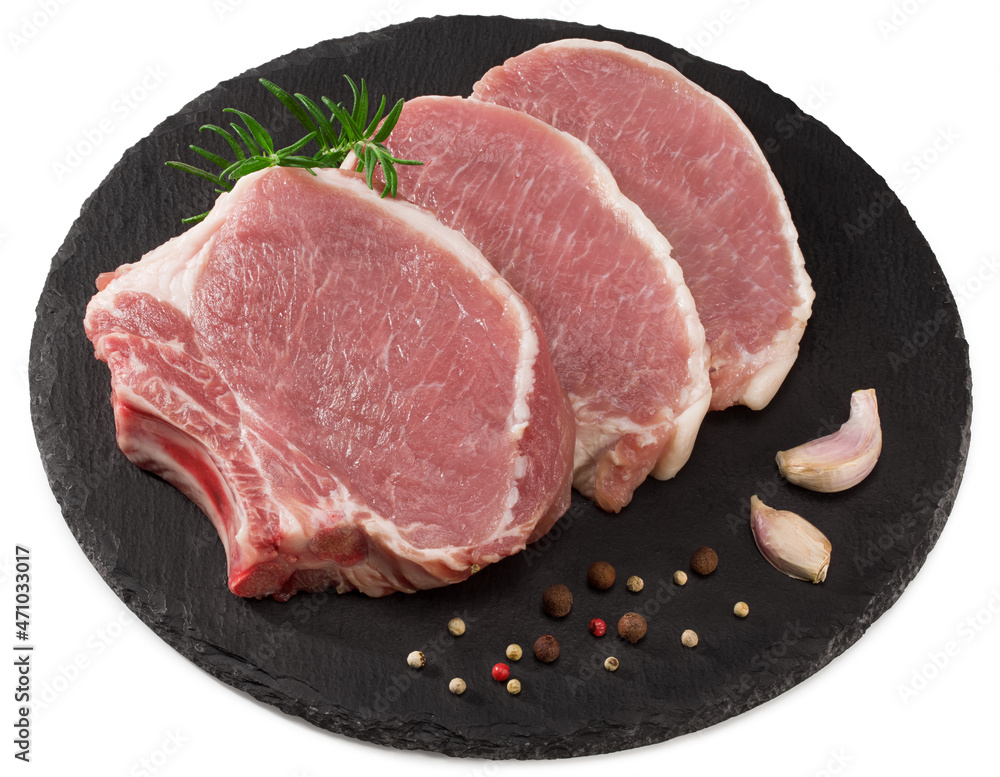 raw pork meat with rosemar, garlic and peppercorn on black round stone plate isolated on white background. Clipping path and full depth of field. Top view raw pork meat with rosemar, garlic and peppercorn on black round stone plate isolated on white background. Clipping path and full depth of field. Top view