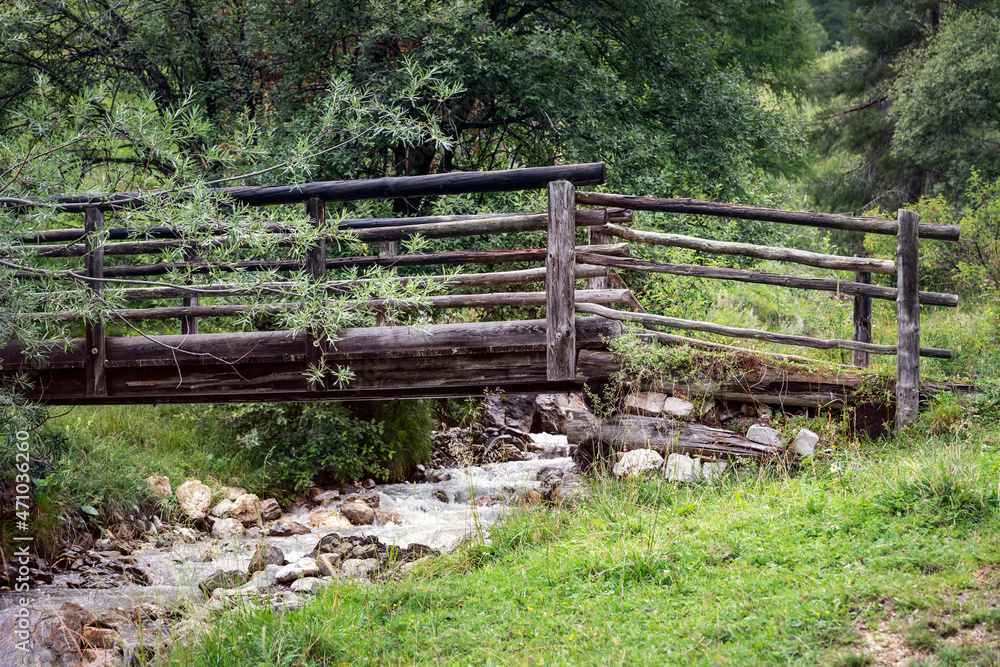 Old wooden footbridge over a stream in the Alps