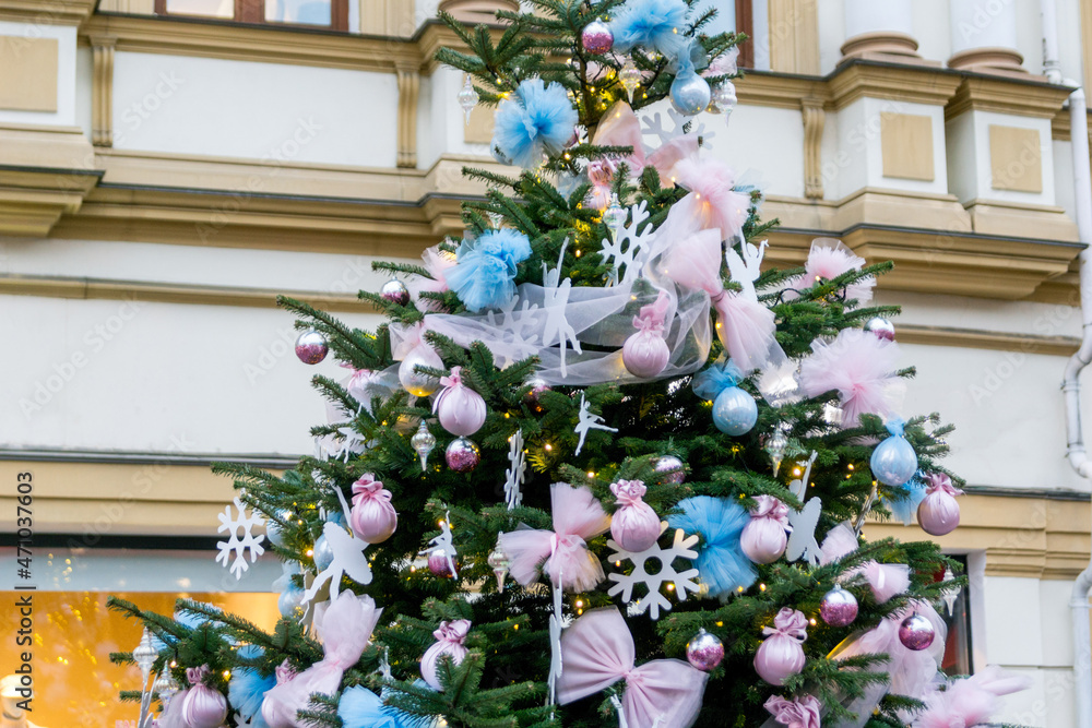 Beautiful Christmas tree on a city street. Blue and pink tulle bows, balls, snowflakes and ballerinas as decorations on the fir tree.