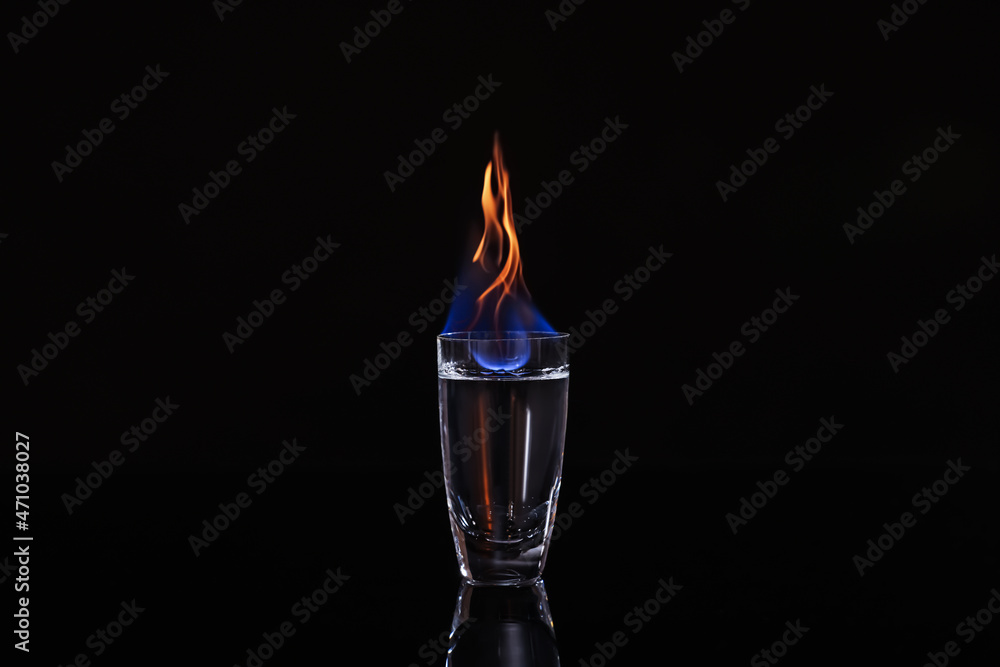 Flaming vodka in shot glass on black background Flaming vodka in shot glass on black background