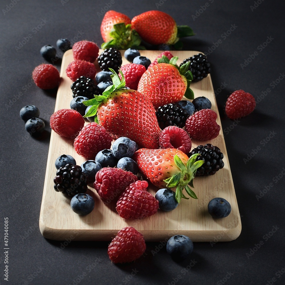 Obraz premium A mixture of strawberries, blackberries, raspberries and blueberries on a cutting board ready to be processed into a healthy diet. 