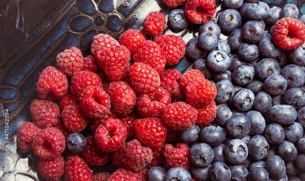 Raspberries and blueberries background. Natural summer vitamins in the diet Raspberries and blueberries background. Natural summer vitamins in the diet