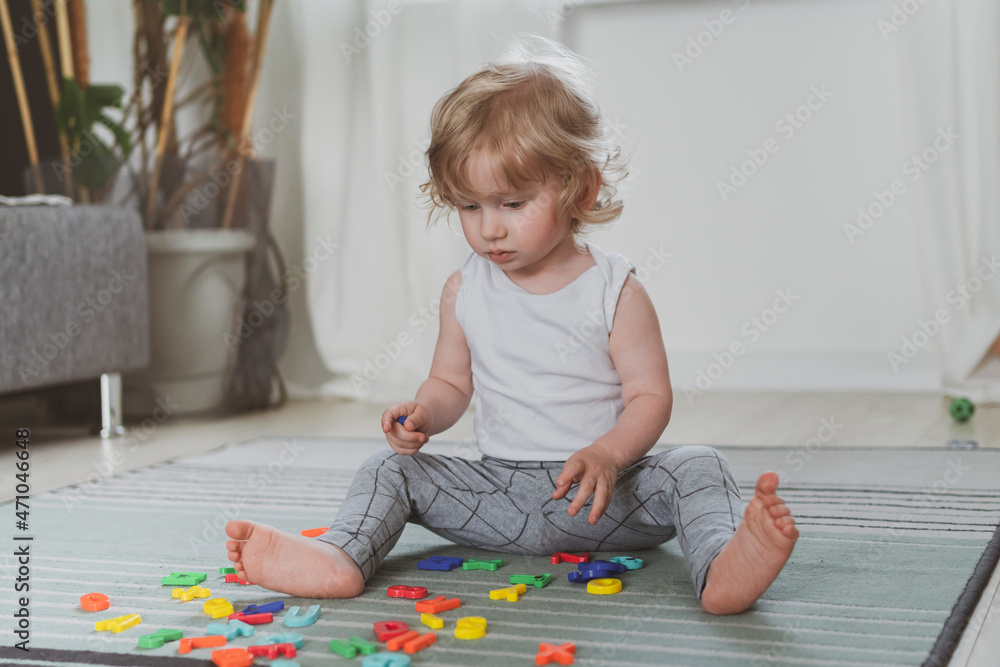 little cute toddler playing with toy letters sitting on the floor little cute toddler playing with toy letters sitting on the floor