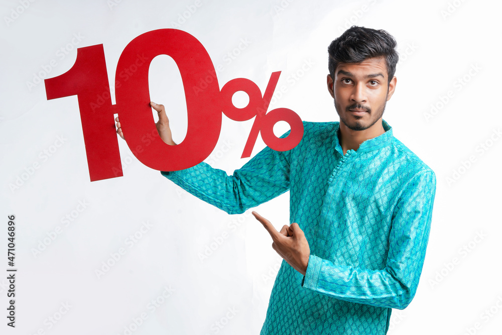Indian man holding ten percent sign board promoting offers on festival season while wearing traditional cloths. Indian man holding ten percent sign board promoting offers on festival season while wearing traditional cloths.