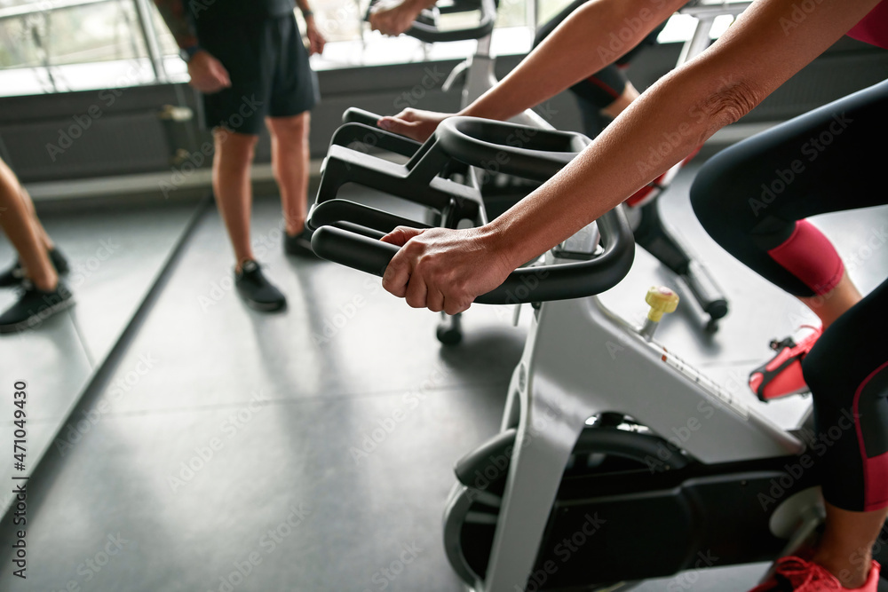 Female hands on exercise bike handlebars Female hands on exercise bike handlebars