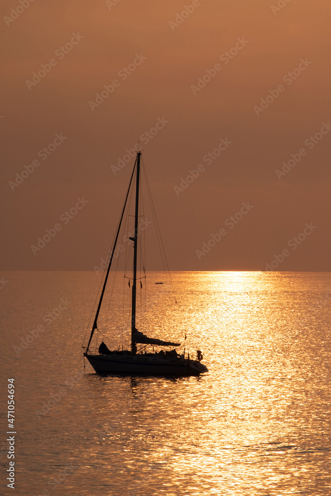 View on the sailboat in the ocean on the sunset in the golden light, close to the beach of Morro Jable on the Canary Island Fuerteventura.