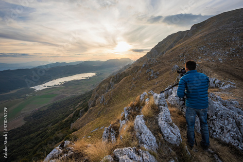 View of a person standing on the rocks taking photos from mountain top at Matese lake, Campania, Italy. photo