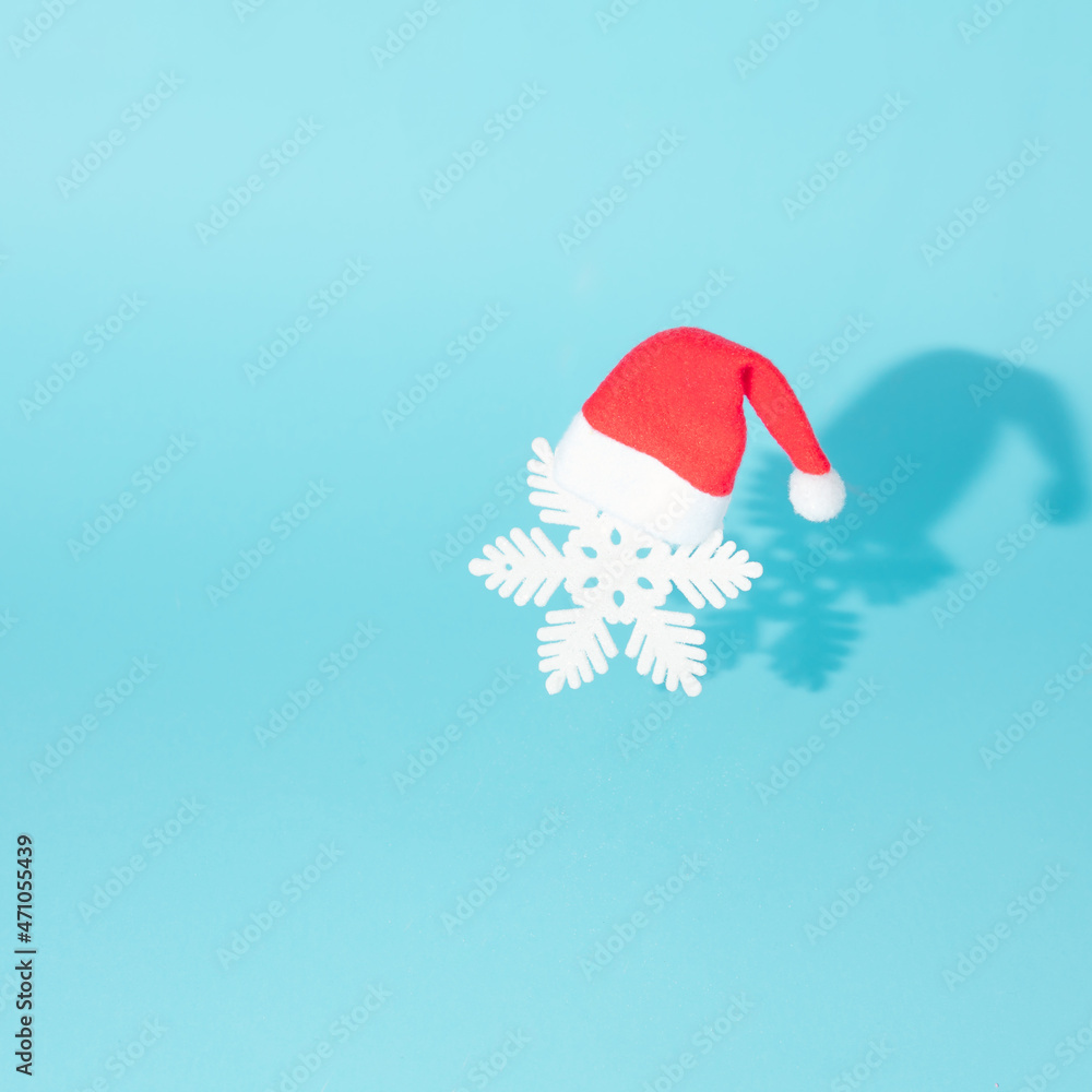 Snowflake with Santa Claus hat on a light blue background.Winter holidays in the snow creative concept. Surreal seasonal artistic design. Snowflake with Santa Claus hat on a light blue background.Winter holidays in the snow creative concept. Surreal seasonal artistic design.