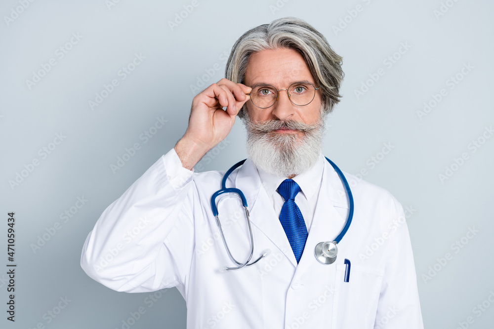 Photo of serious clever mature male doctor wear white coat arm glasses isolated grey color background Photo of serious clever mature male doctor wear white coat arm glasses isolated grey color background