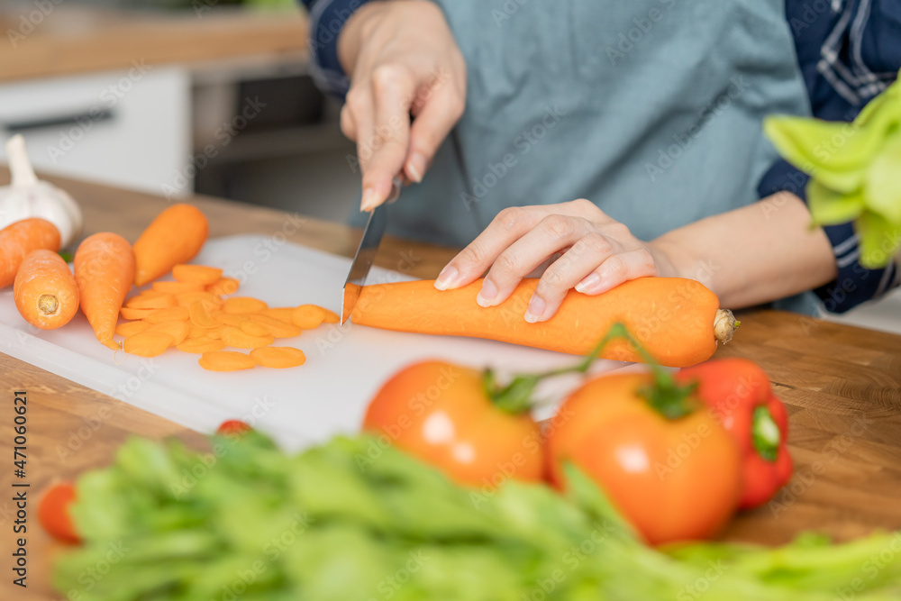 Asian young woman, girl or housewife using knife, cutting carrots on board, on wooden table in kitchen home, preparing ingredient, recipe fresh vegetables for cooking meal. Healthy food people. Asian young woman, girl or housewife using knife, cutting carrots on board, on wooden table in kitchen home, preparing ingredient, recipe fresh vegetables for cooking meal. Healthy food people.
