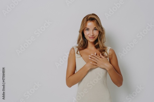 Фотография Lovely young female model presses palms to heart expresses gratitude says thank
