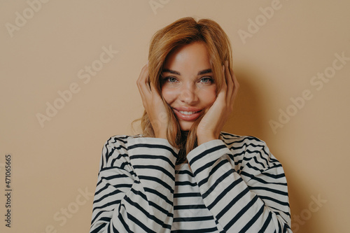 Happy young woman looking at camera with joyful facial expression holding her face with both hands © VK Studio