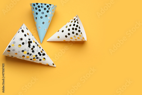 Bright party hats on orange background, flat lay. Space for text