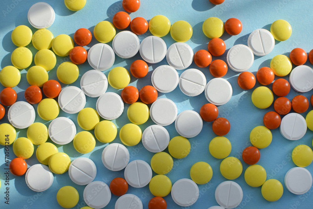 Antiviral white, yellow and orange pills for treatment on a blue background. Flat lay, top view