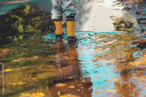 Child with rubber rain boots walking on wet sidewalk in autumn afternoon © Bits and Splits